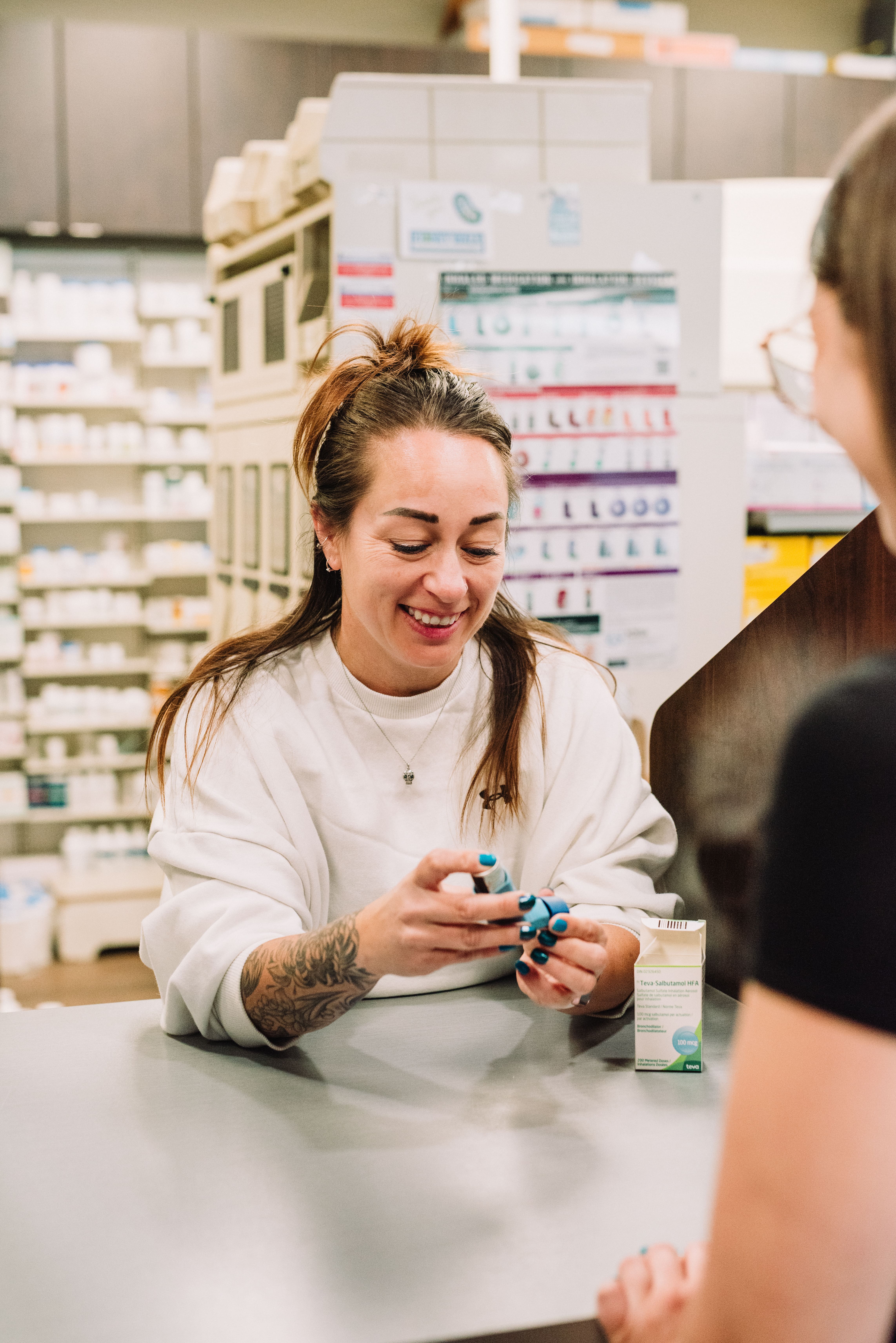 Pharmacist at Kipp-Mallery Pharmacy in Kamloops explaining inhaler use to a patient at the counter