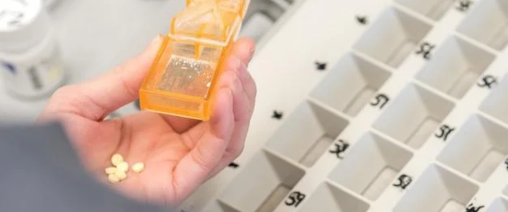 Close-up of pharmacy staff organizing prescription pills into medication blister packs to help patients manage daily doses safely and conveniently.